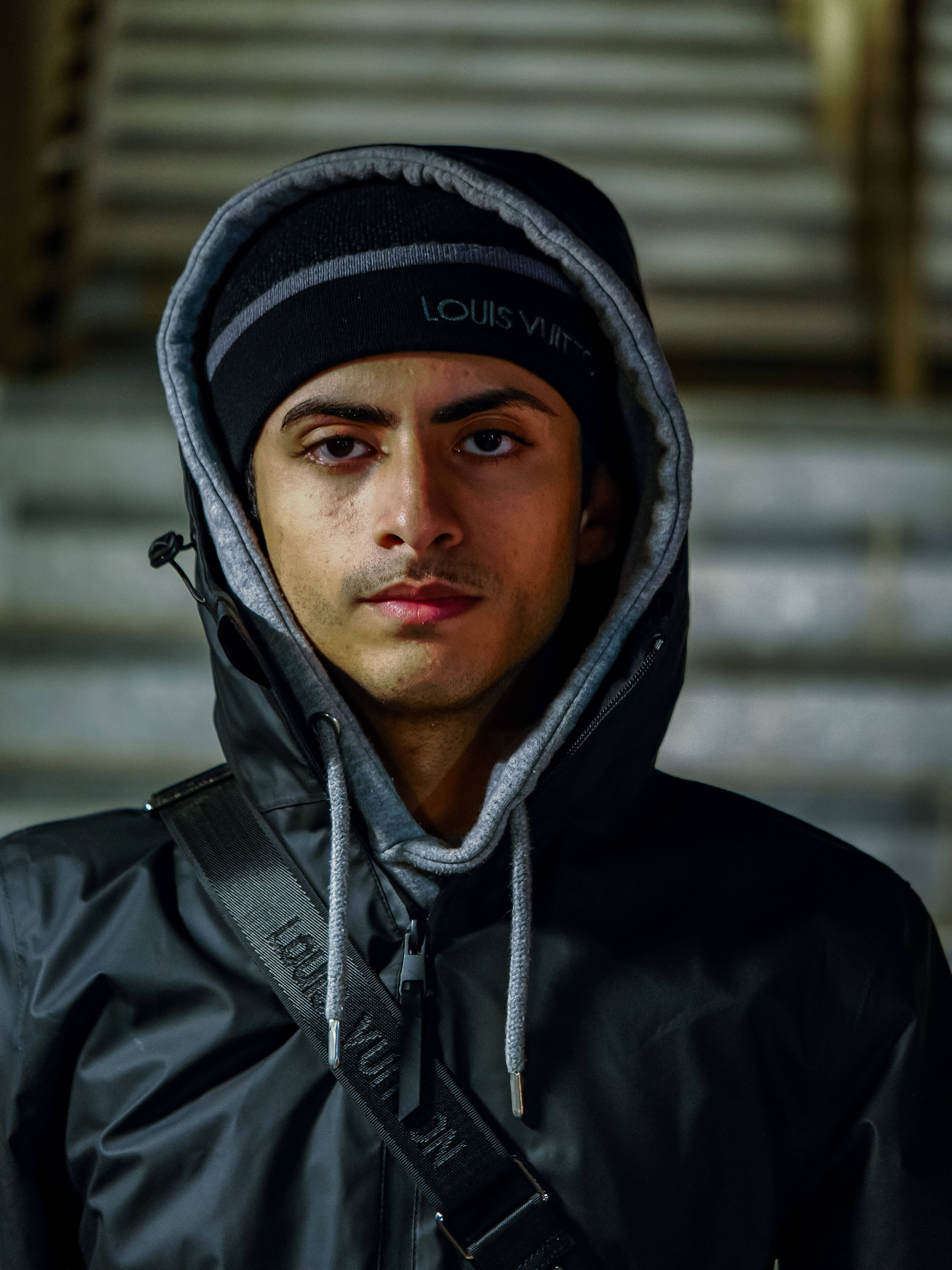Person wearing a black Louis Vuitton jacket with a hood in an urban setting